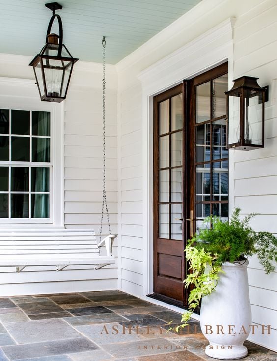 porch with wooden door and white bench swing