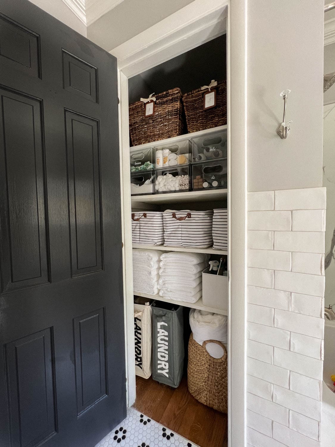 organized bathroom linen closet with bins, baskets, and towels