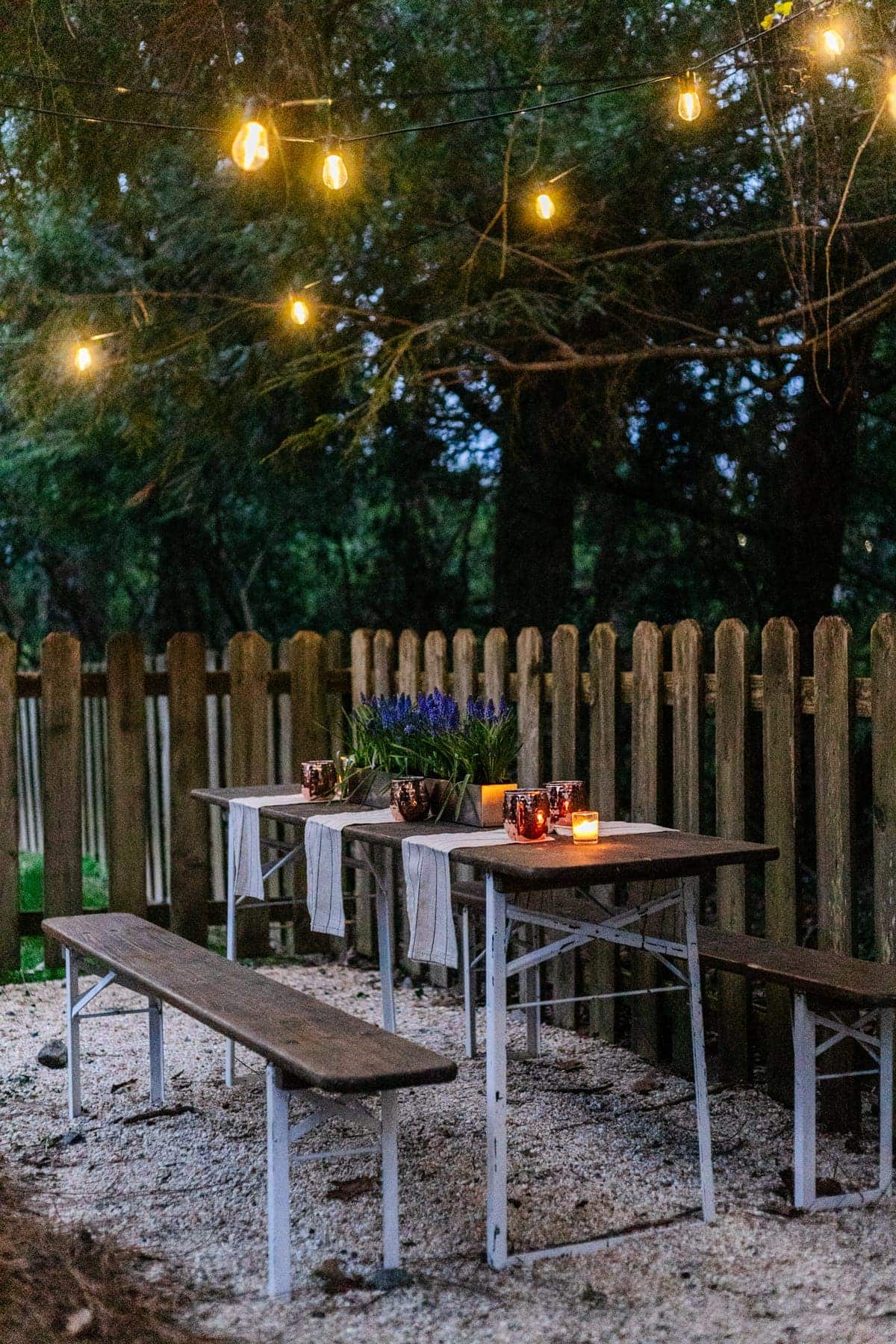 folding table and string lights on pea gravel for an inexpensive backyard patio area