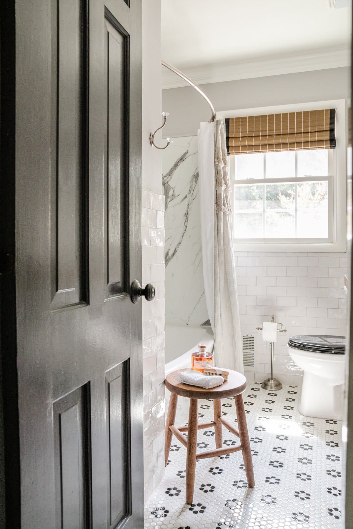 black and white bathroom with subway tile, black door, and retro tile floor