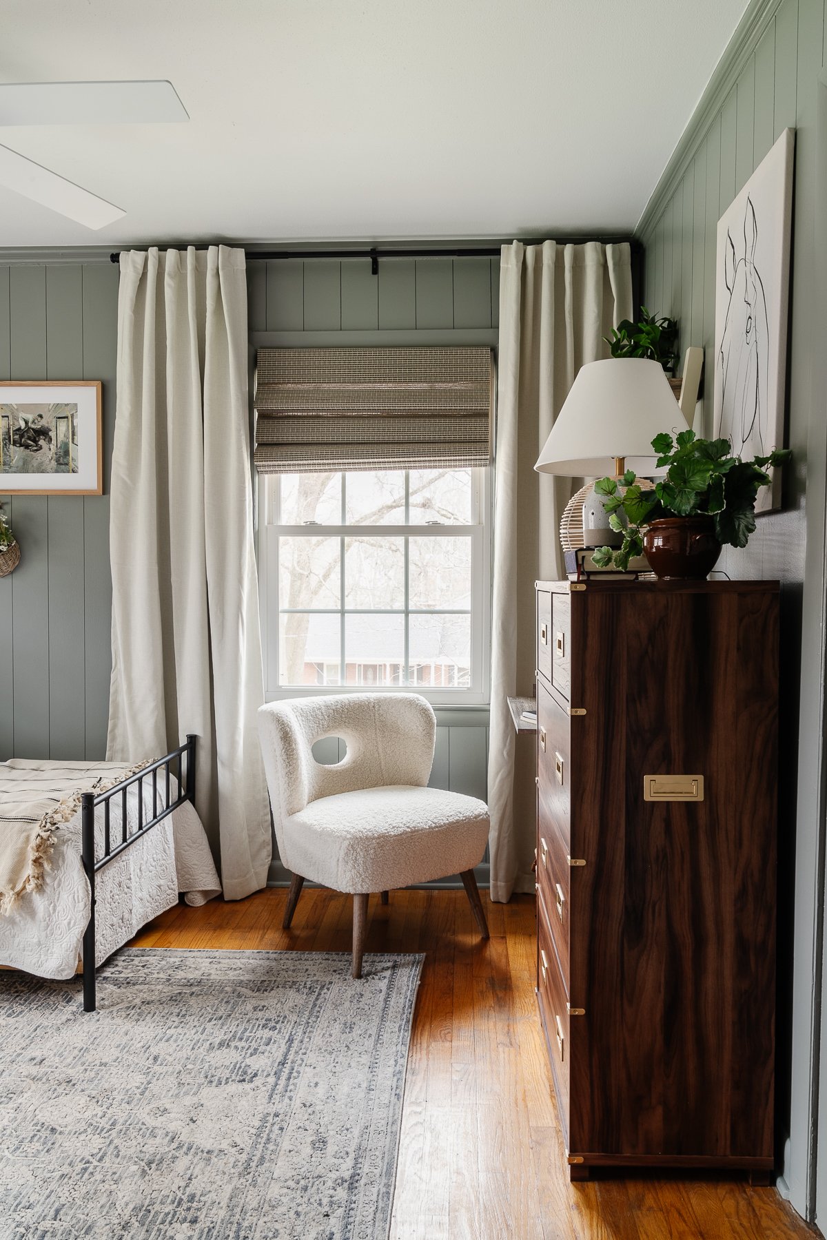 bedroom painted Sherwin Williams Evergreen Fog with wood dresser and white boucle desk chair