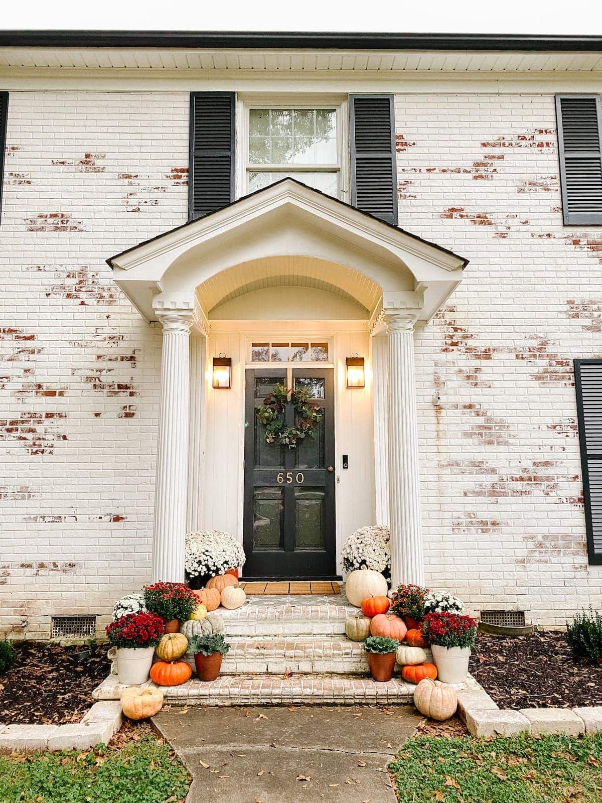 Colorful Fall Porch Stoop Decorated with Mums and Pumpkins with Limewashed Brick