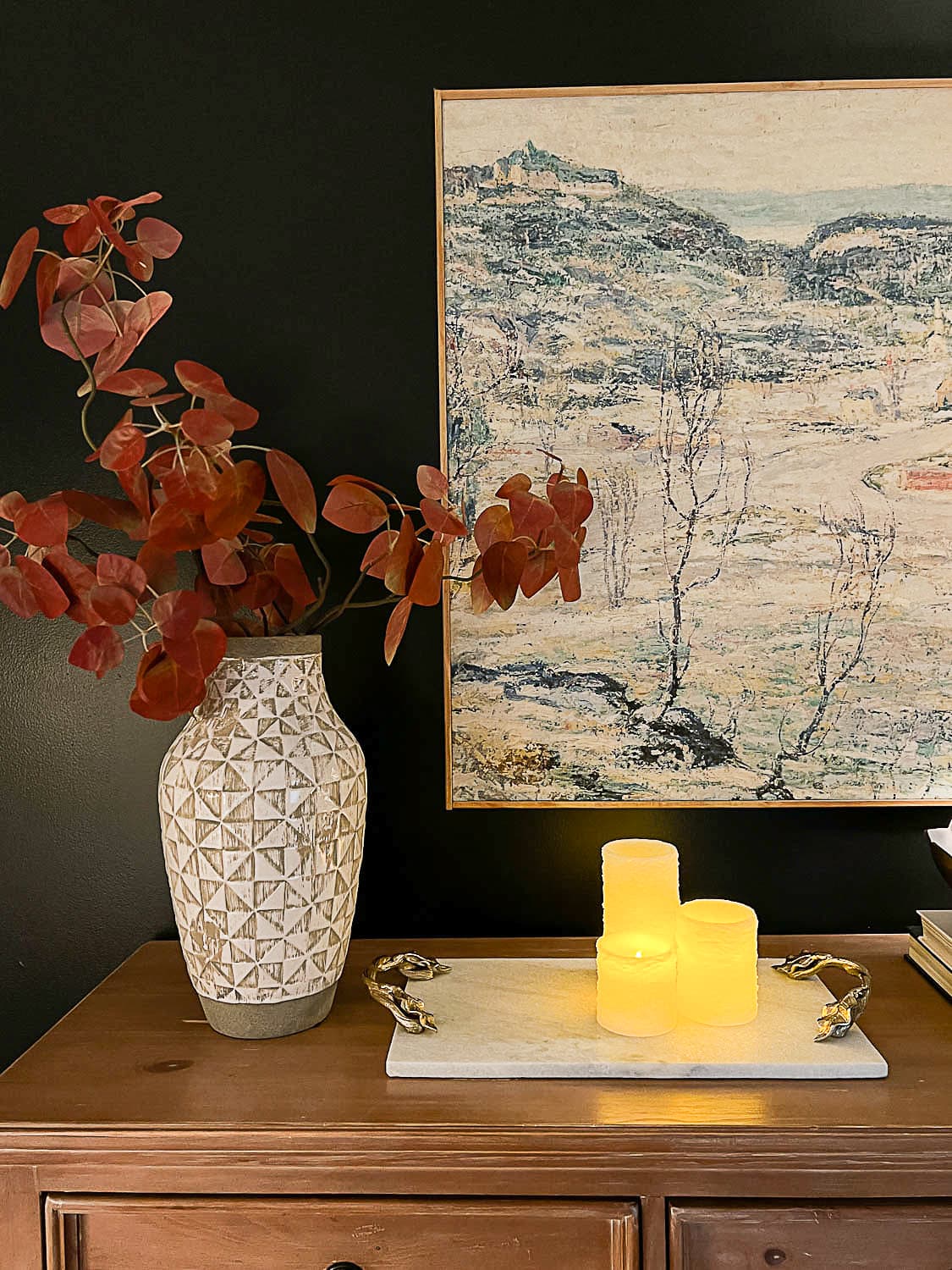 flameless candles, marble tray, vase of fall branches and large wall art on top of dresser