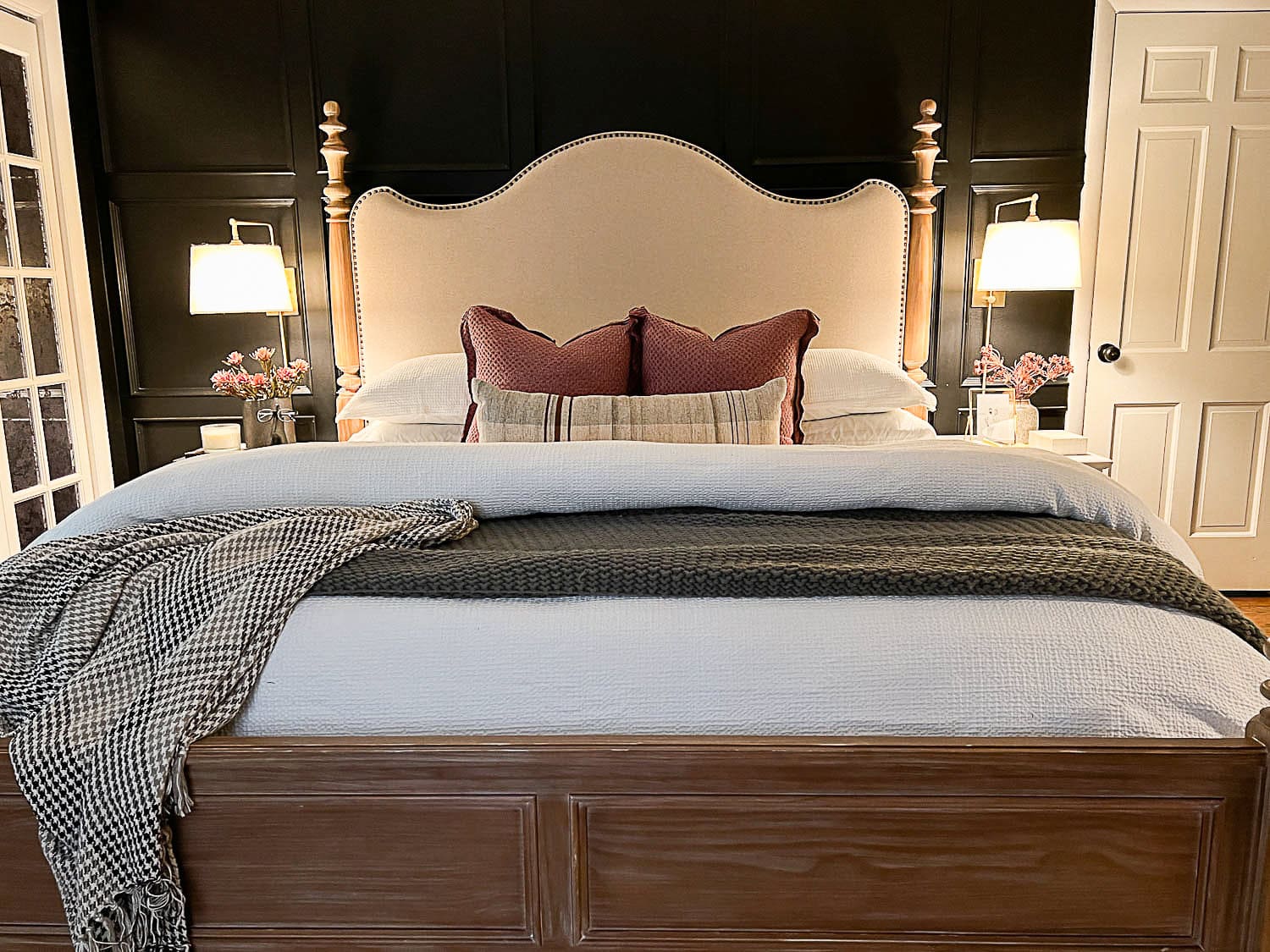 primary bedroom with cozy decor, luxurious bedding, and wall sconce bedside lamps