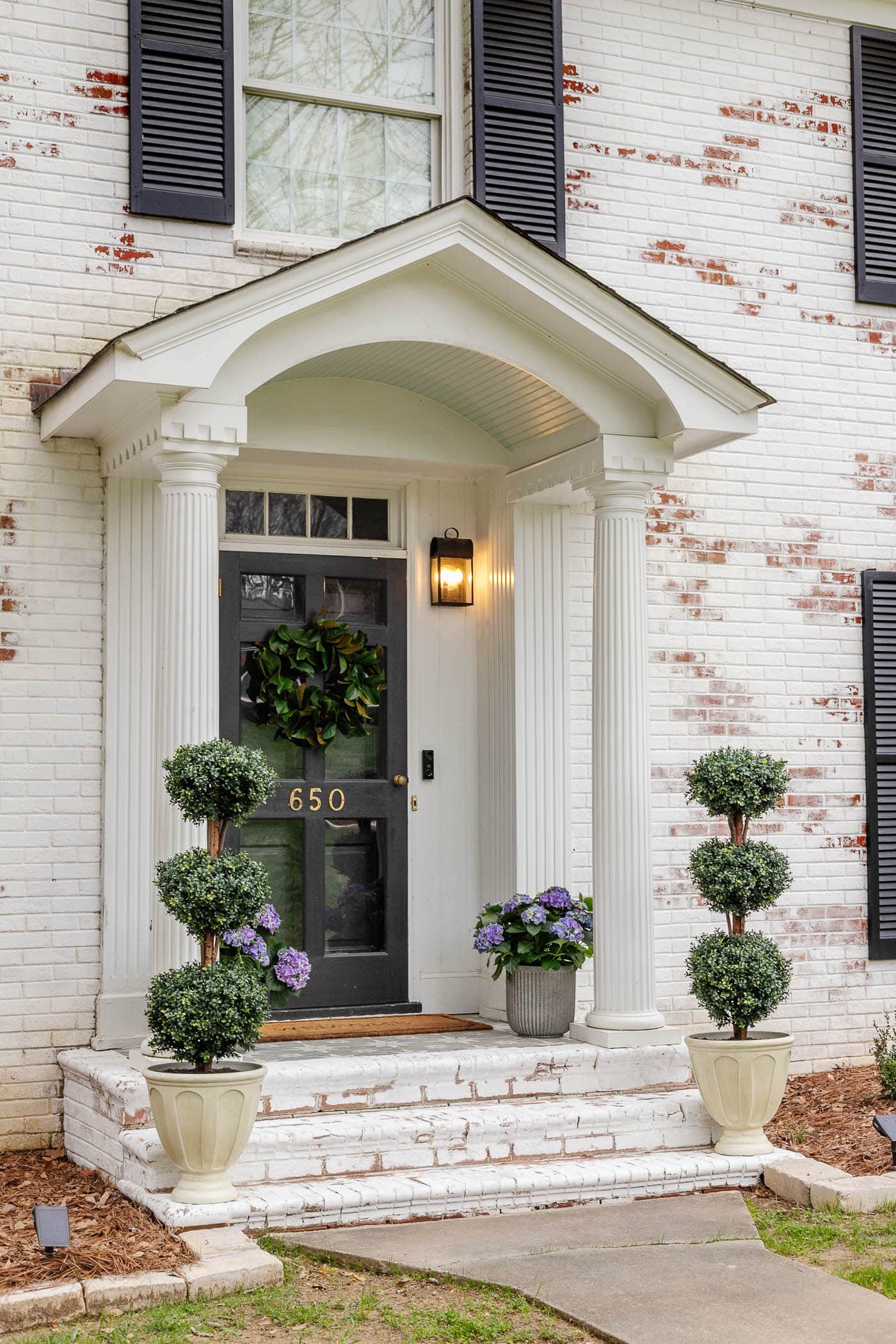 limewash brick steps on a colonial house with small porch decor using symmetrical planters 