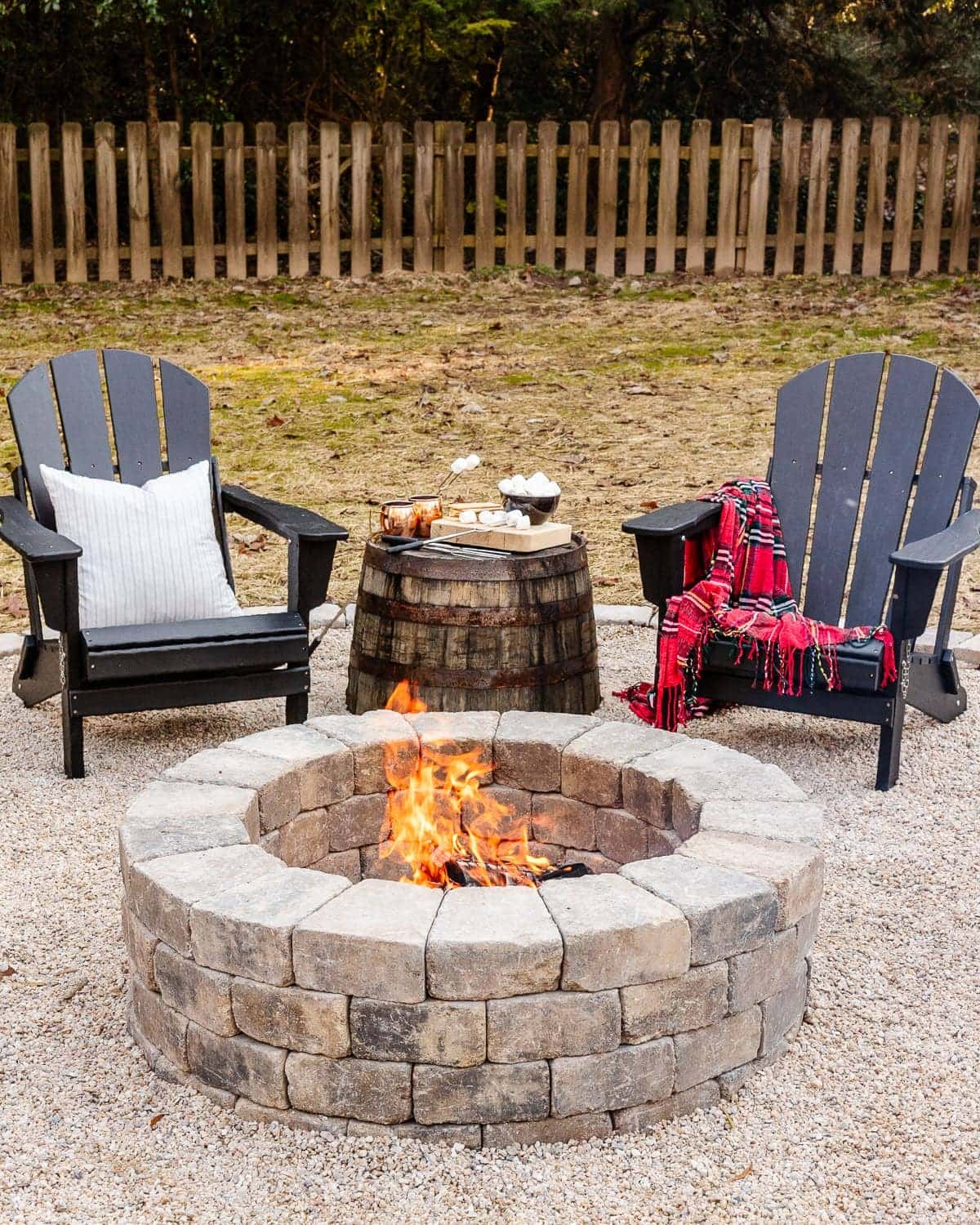 diy stone fire pit in a backyard with adirondack chairs