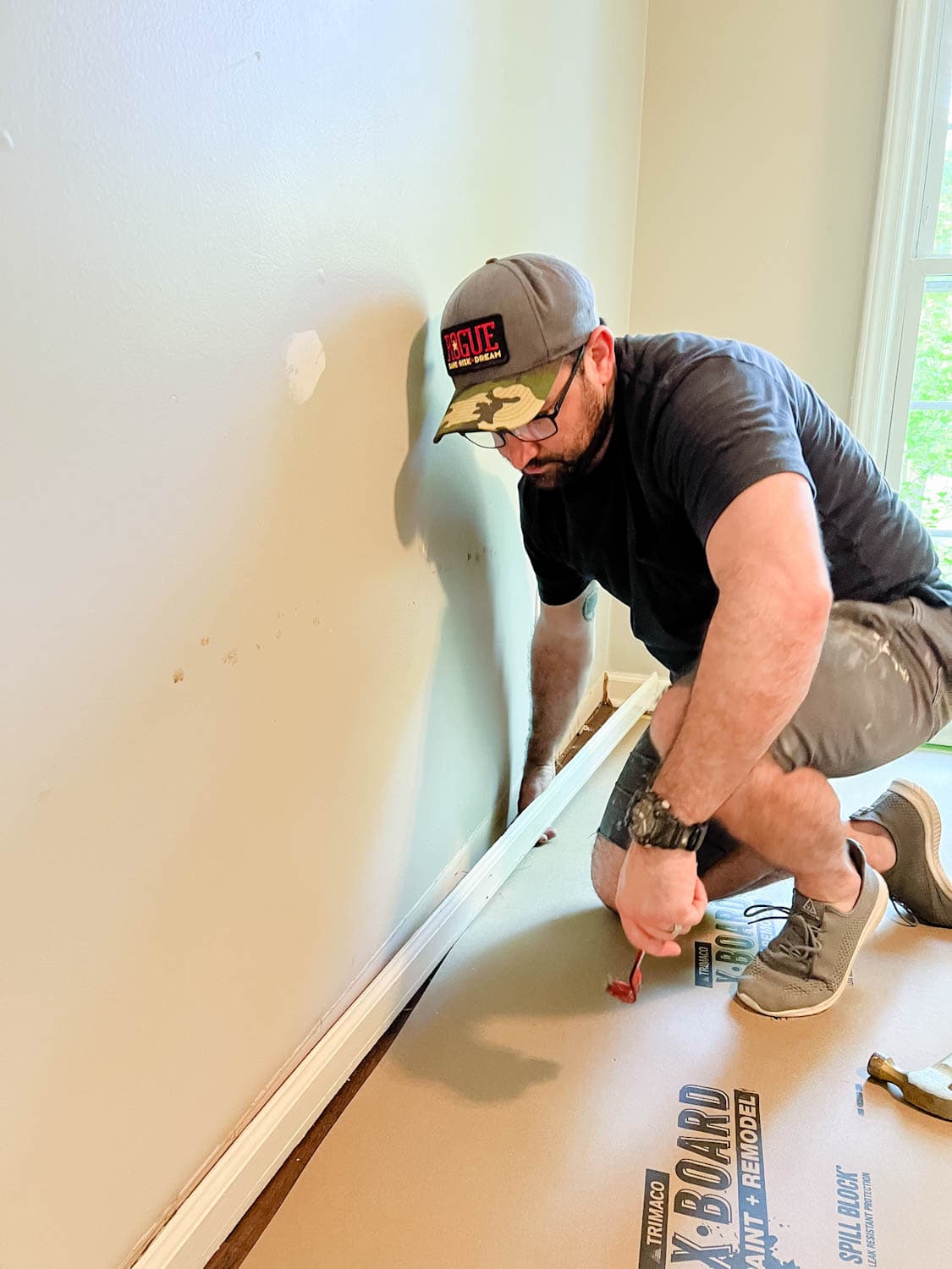removing a baseboard from a wall using a pry bar and hammer
