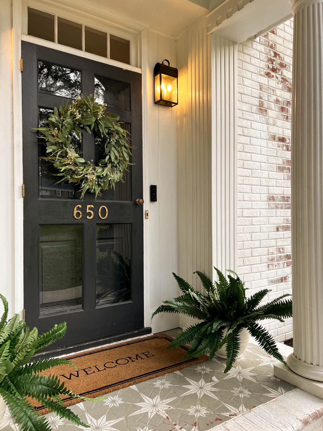 realistic faux wreath and fake ferns on a colonial front porch stoop