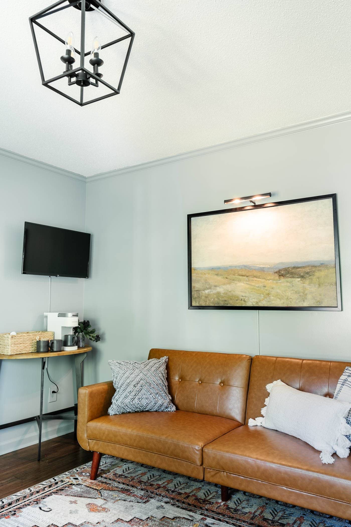 home office lounge ideas including a convertible sofa for guests, a wall-mounted TV, and a coffee station