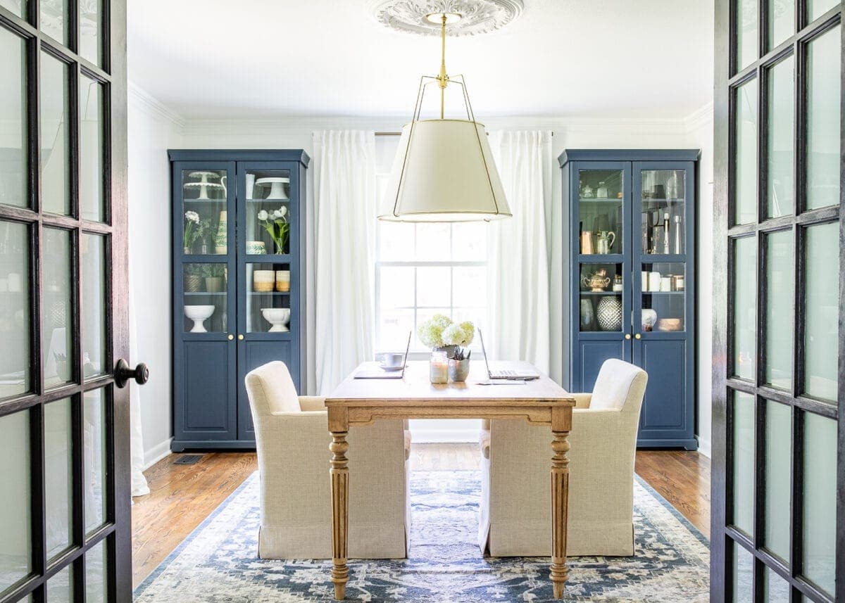 home office with navy blue IKEA cabinets and work table with rolling armchairs