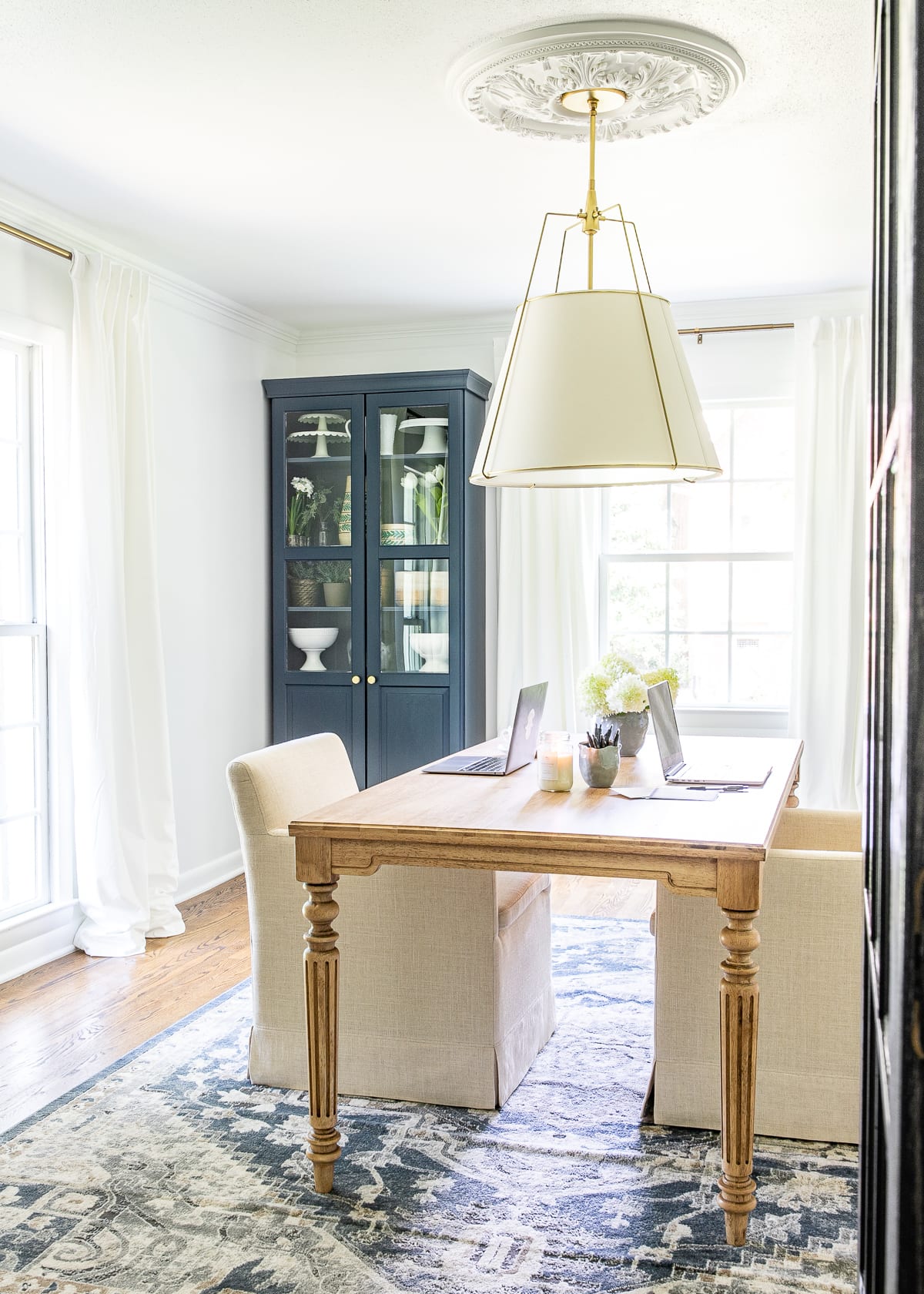 home office with navy blue cabinets, wood work table, and upholstered rolling chairs