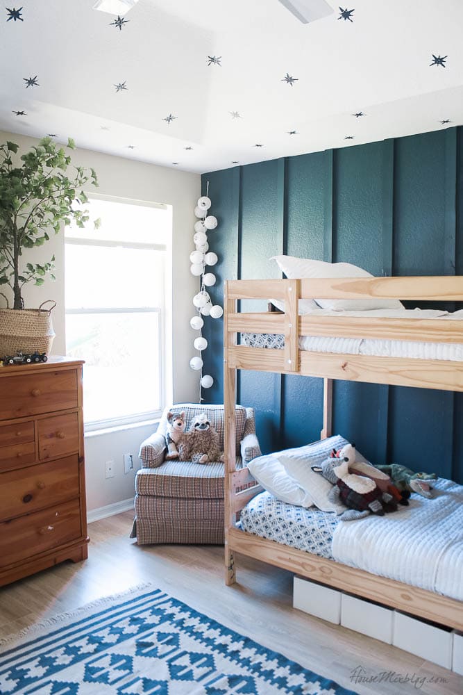 board and batten wall in a small bedroom with wallpaper ceiling