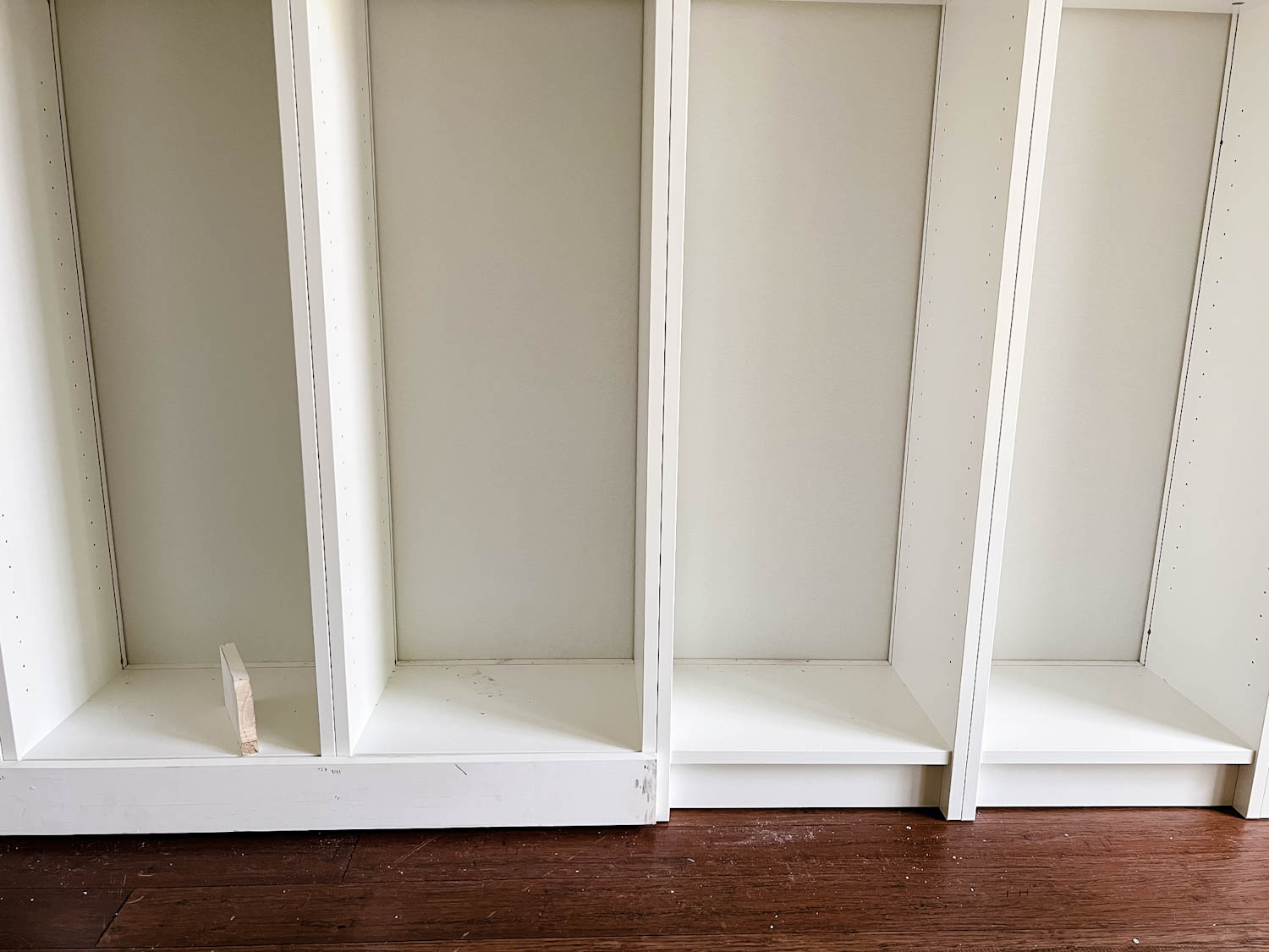 adding 1x4 boards to the bottom of bookcases to make them look flush for DIY built in bookshelves