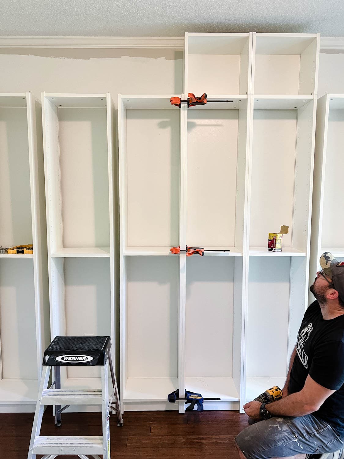 using clamps to keep bookcases together to attach them with wood screws to make diy built in bookshelves