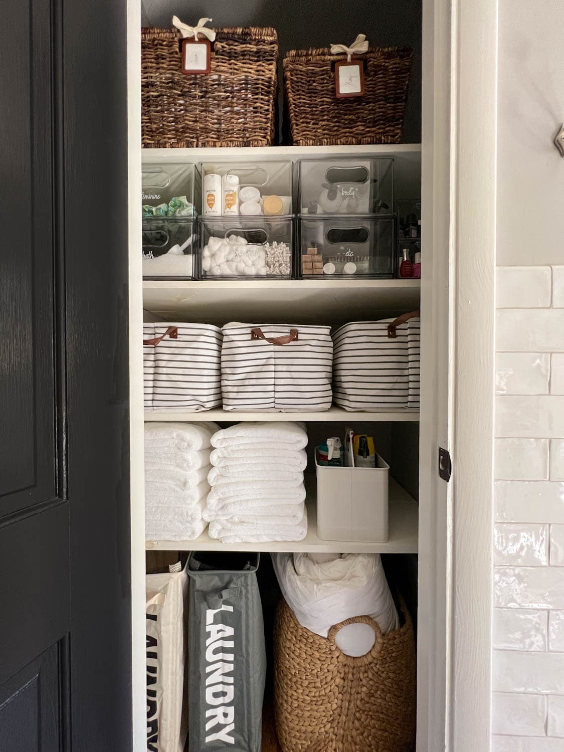 bathroom linen closet organized with bins, baskets, and storage drawers