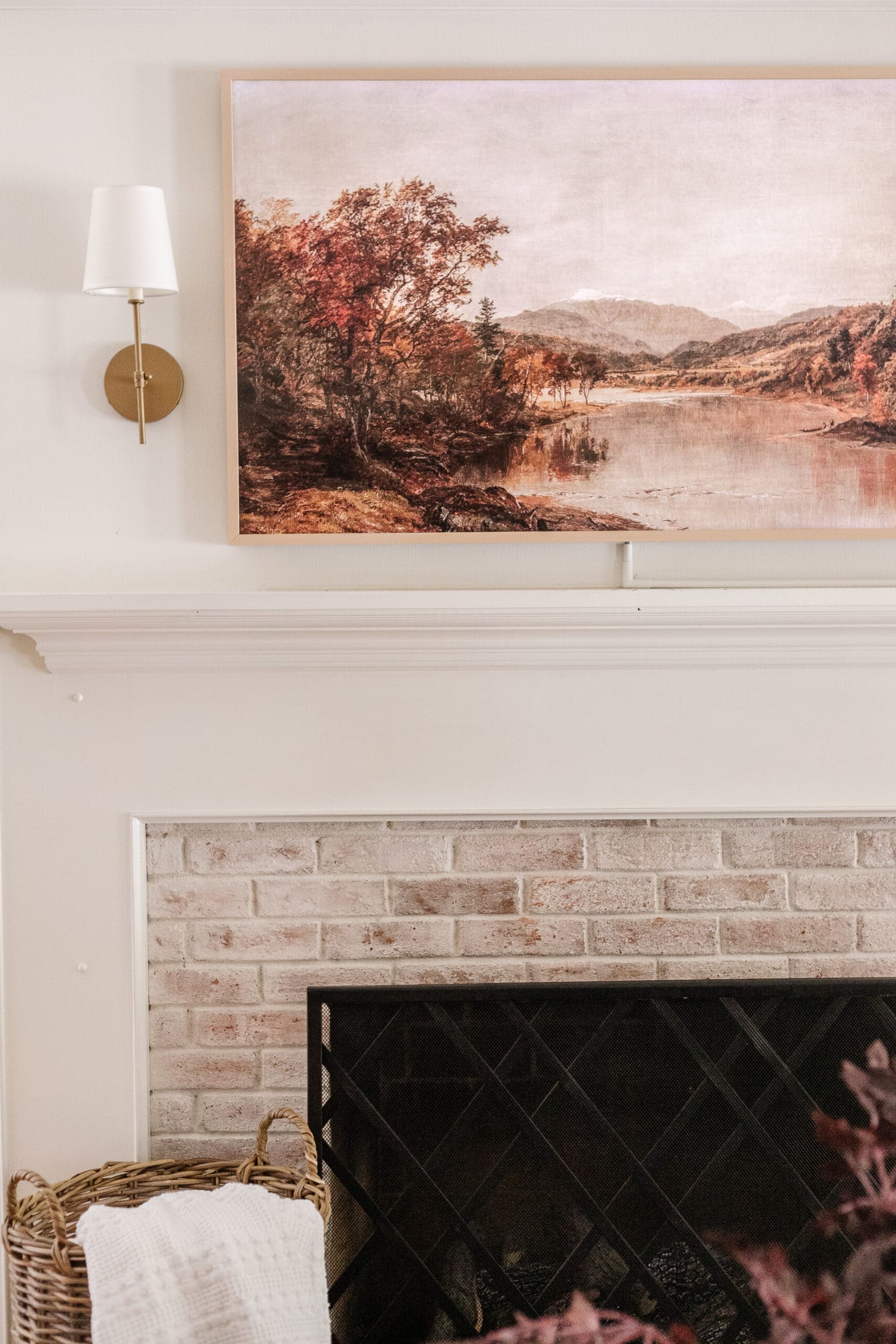 plain beige bezel on a frame TV with gold sconces above a mantel