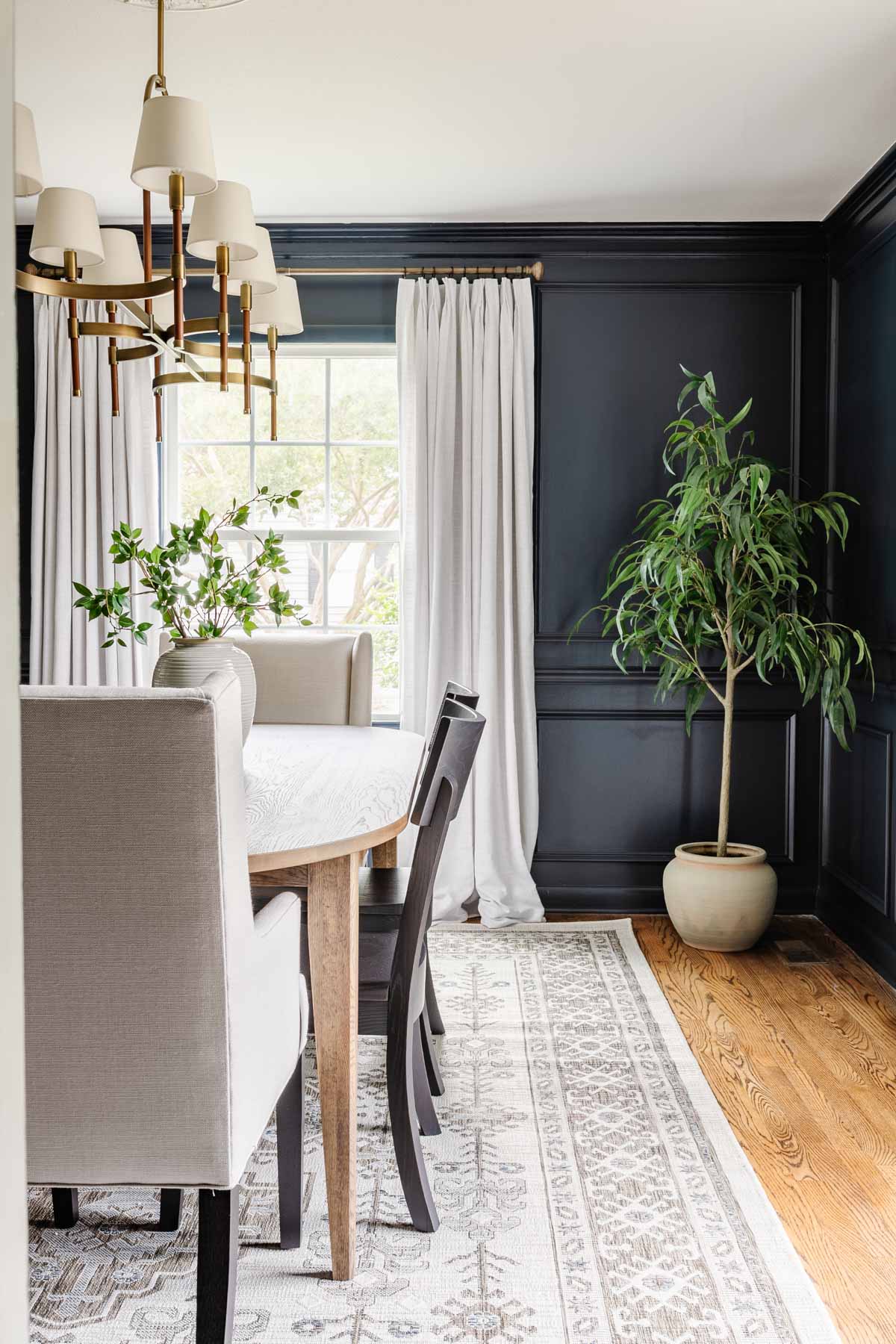 navy blue small dining room with white curtains, Scandinavian rug, and artificial tree