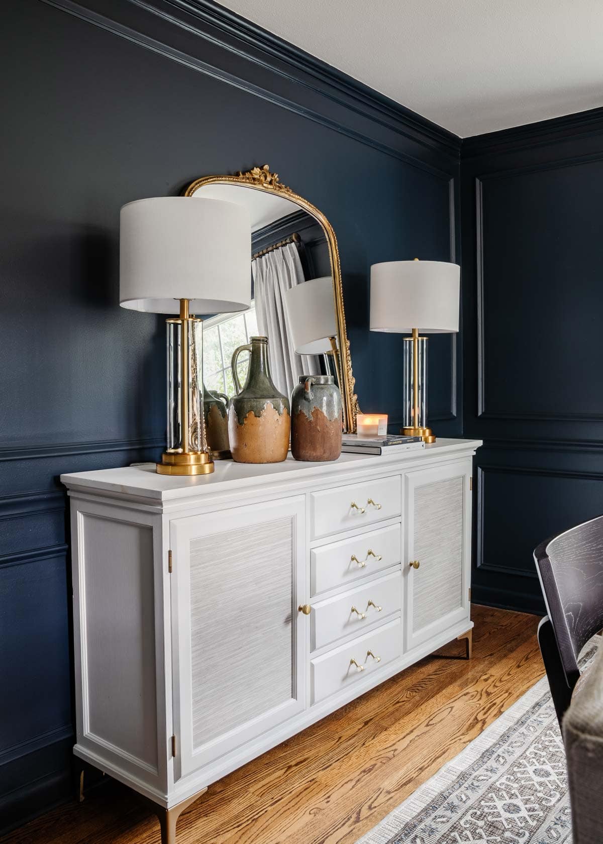 navy blue dining room and white buffet table with picture frame molding and gold mirror