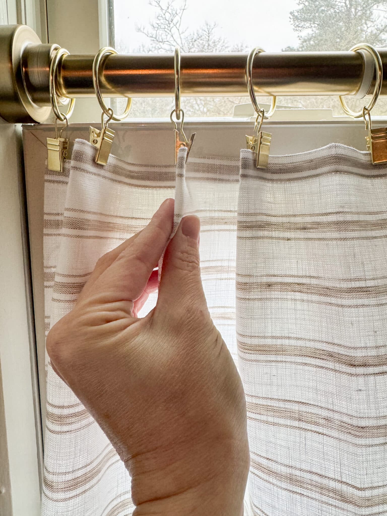 pinching fabric in ring clips to make diy cafe curtains
