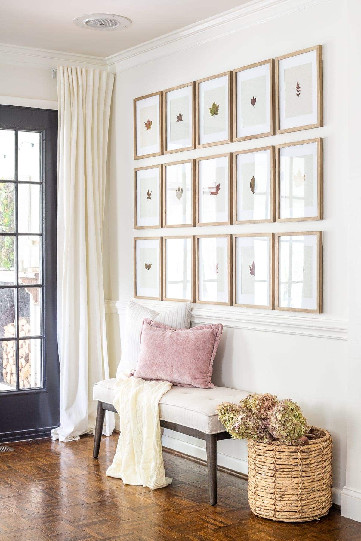 entryway decorated for fall with pressed leaf gallery wall and basket of dried hydrangeas