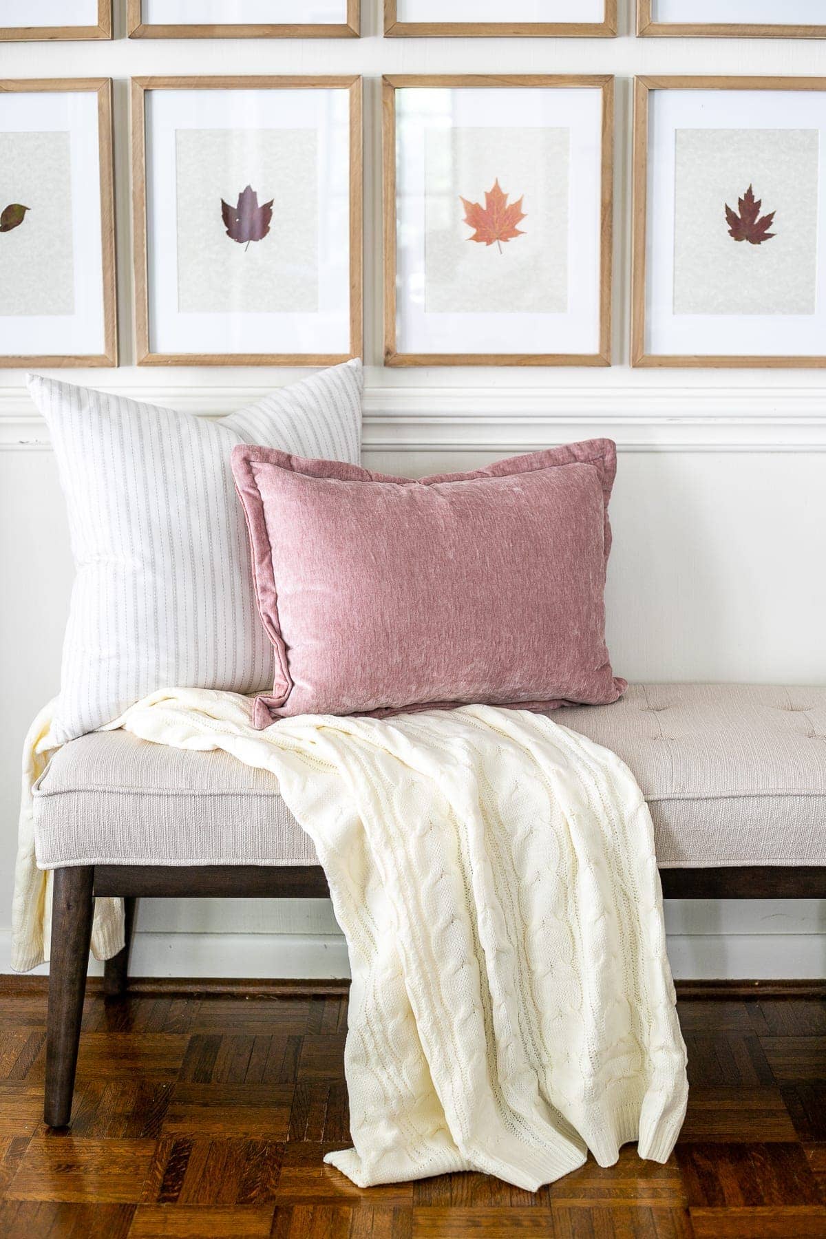 pressed fall leaves in frames and throw pillows on an entryway bench
