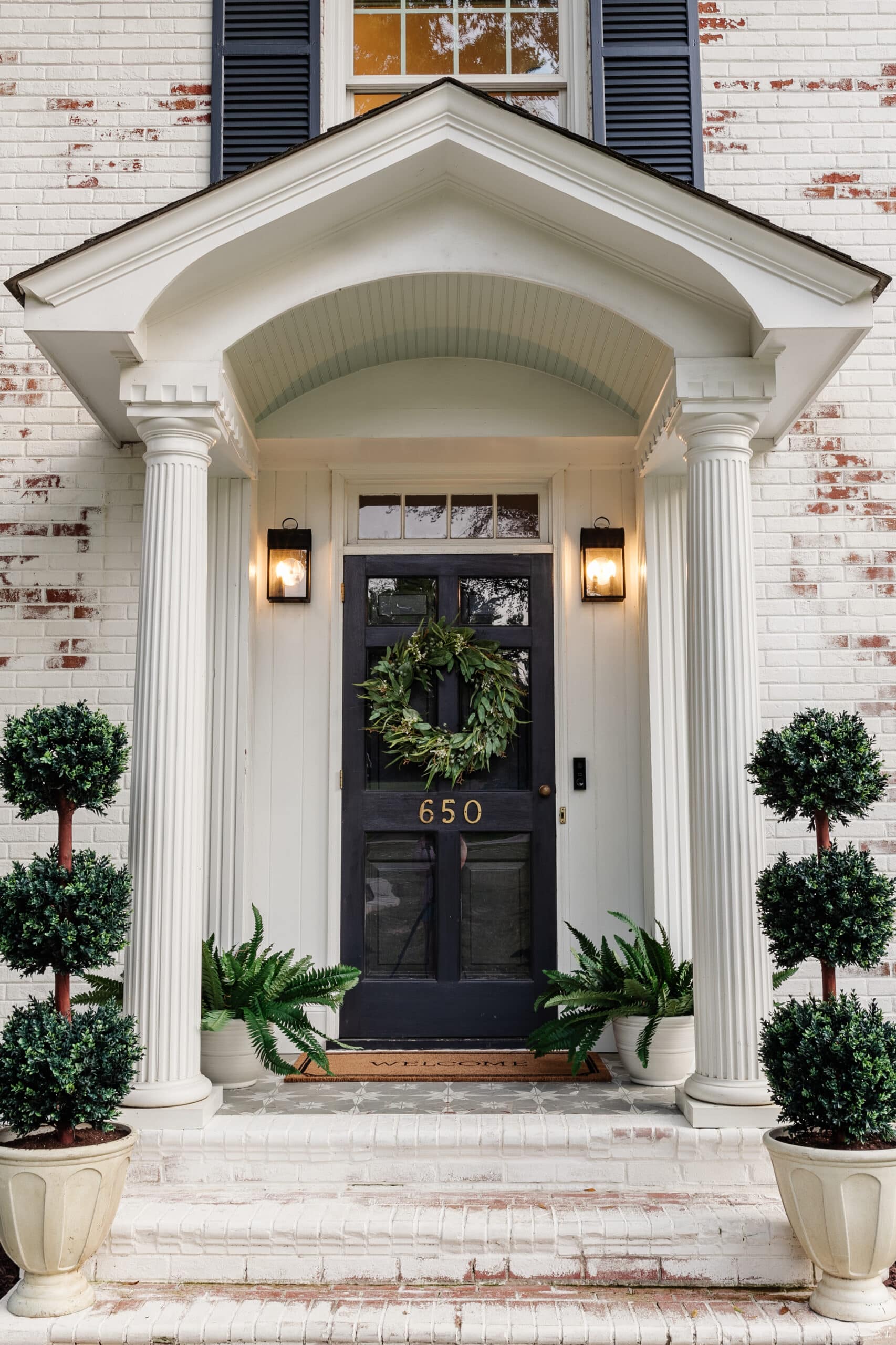 colonial house front porch stoop with faux outdoor plants in planters