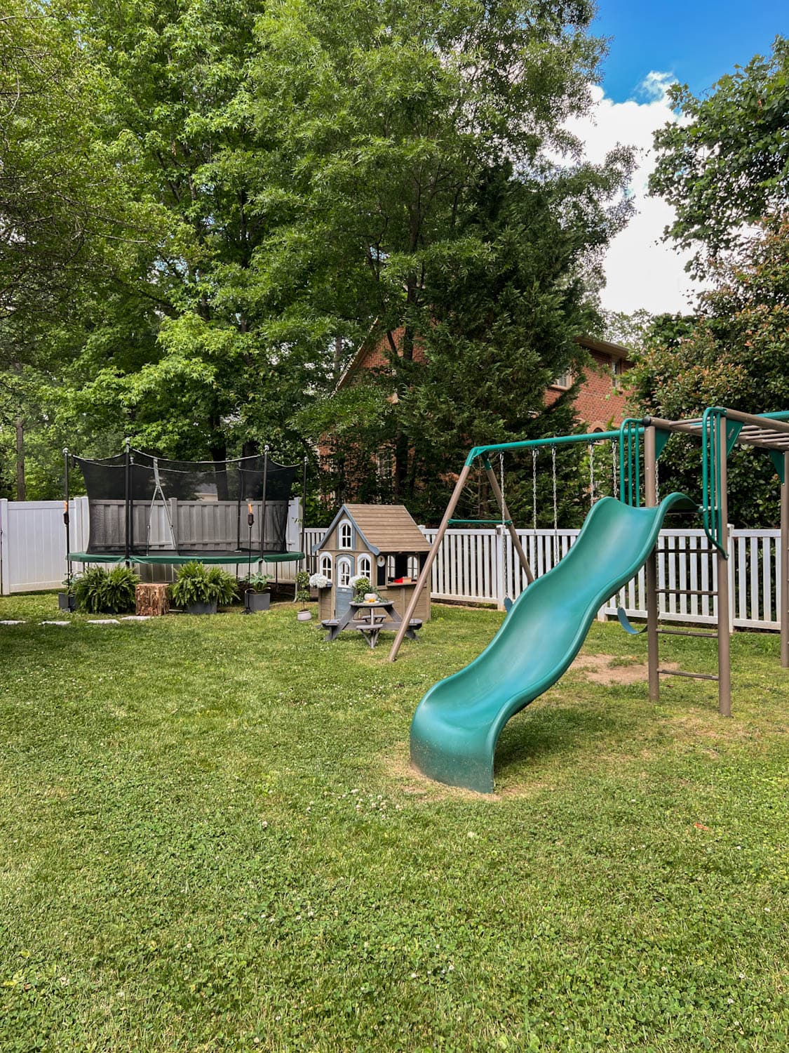 side yard play area for kids with trampoline, outdoor playhouse, and swing set