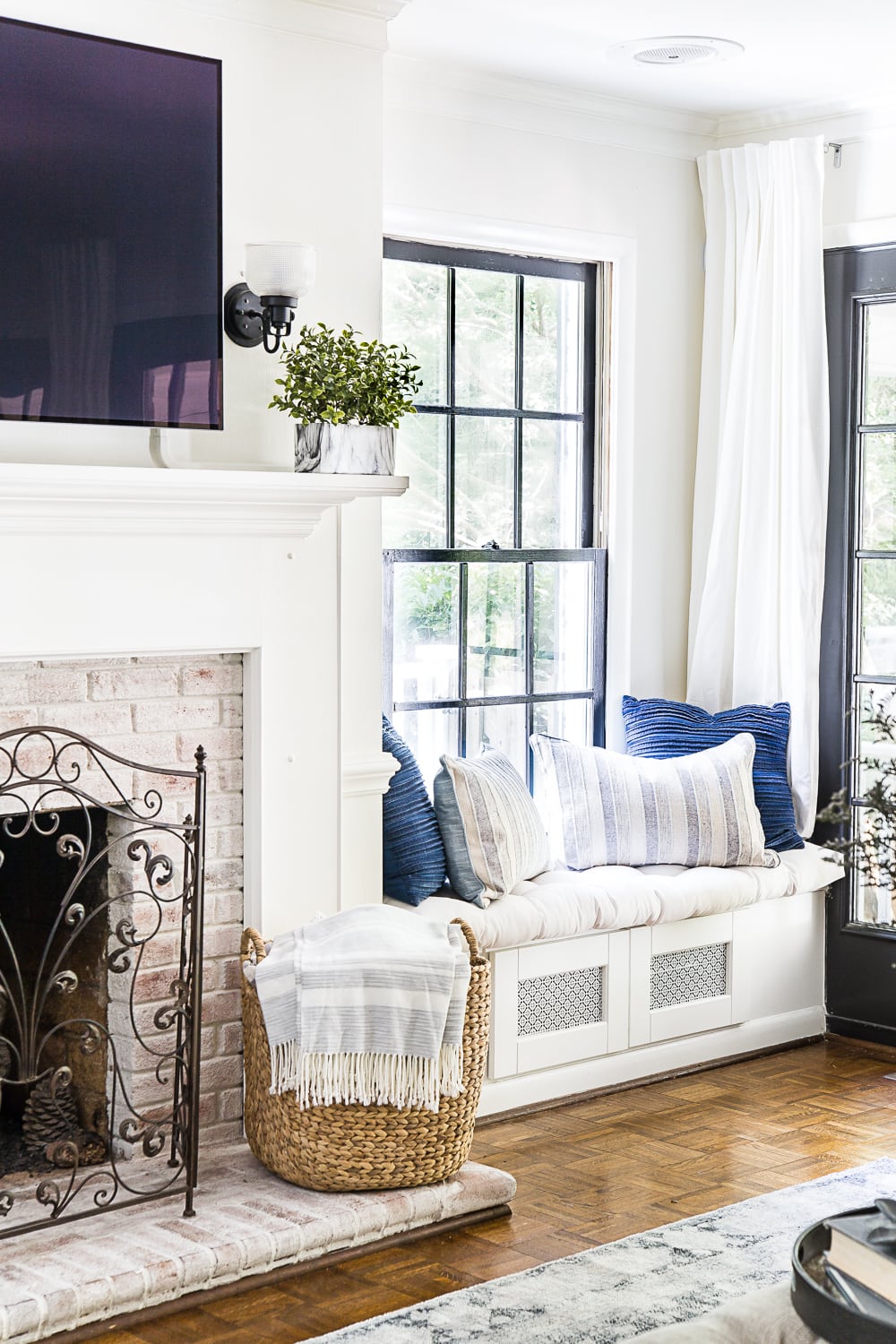 living room with window seat for electronics storage and limewashed fireplace