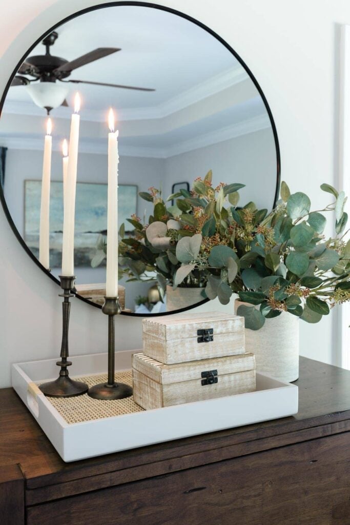candles, tray, and vase of greenery in front of mirror