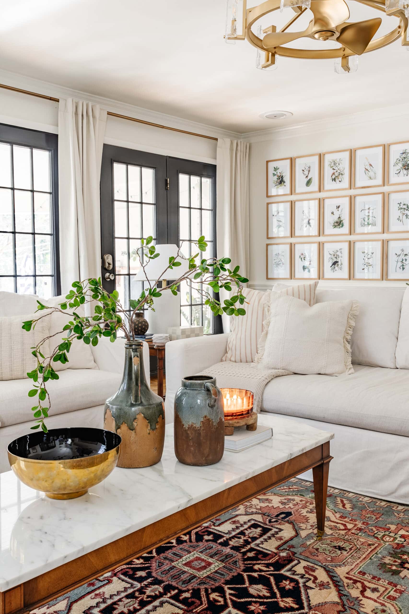 winter living room January decor with white sofas, candle, and vase of greenery on coffee table